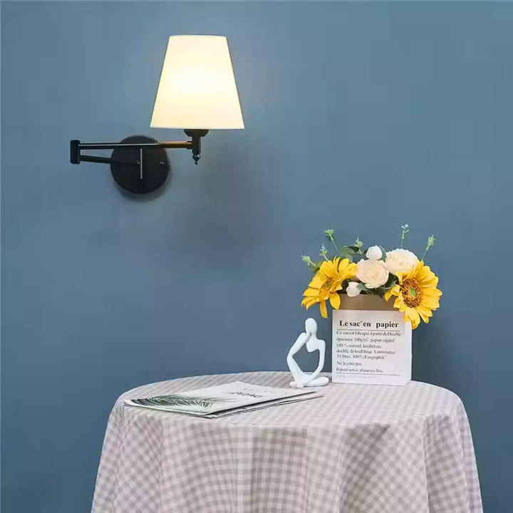 Luminária de parede articulada preta em parede azul sobre uma mesa lateral com girassóis