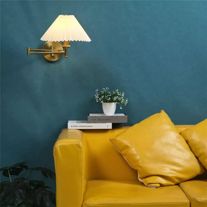 Luminária de parede plissada dourada em uma sala de estar elegante acima de um sofá