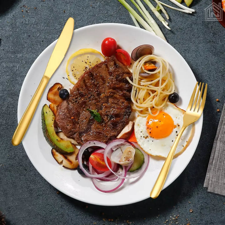 prato de comida usando jogo de talheres dourados com carne macarrão ovo e legumes