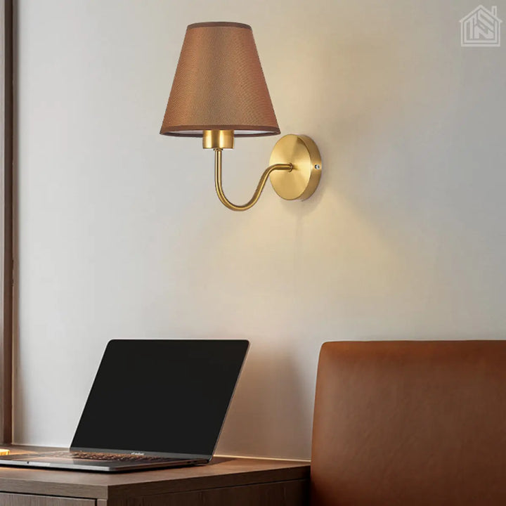 luminária-de-parede-cúpula-marrom-com-suporte-dourado-em-um-quarto-com-notebook-e-sofá